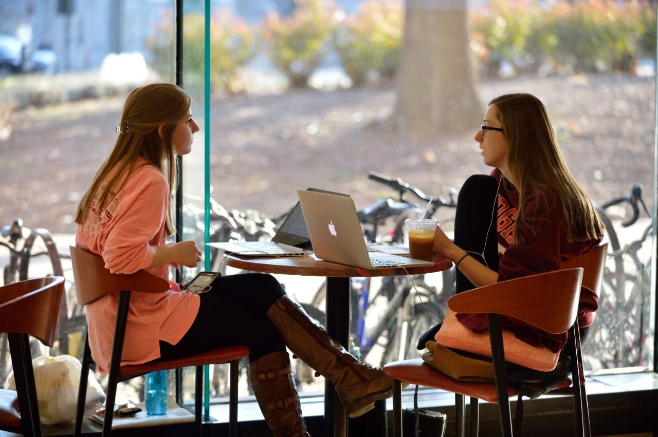 Two female students talking at a table in the cafe.