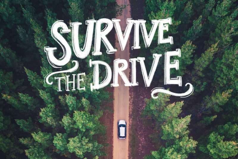 "Survive the Drive," floats over a car on a forest road.