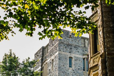 Abstract scene of a Hokie stone building with summer leaves in the foreground