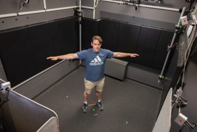 A student employee holds his arms out in middle of the camera set up to test the system.