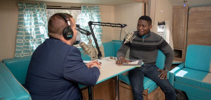 An interviewer recording an oral history in a recreational vehicle.