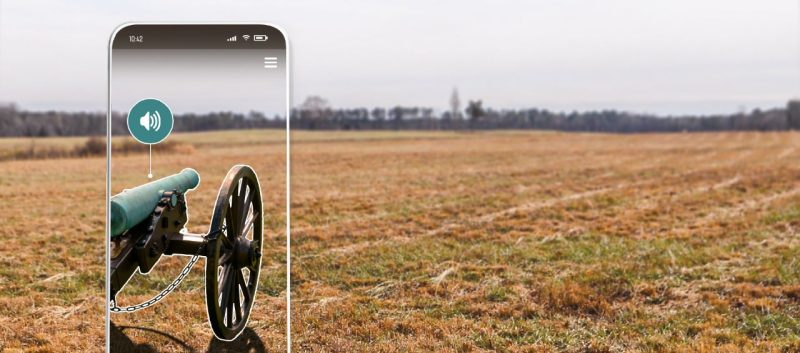 A cannon appears as an augment reality overlay on a phone screen with the Pamplin Historical Park behind it.