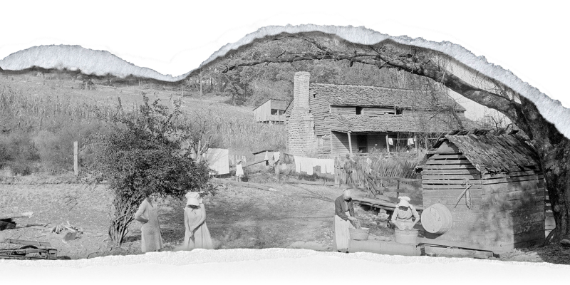 A small group of people cook, clean, and hang clothes outside a cottage on a hillside.