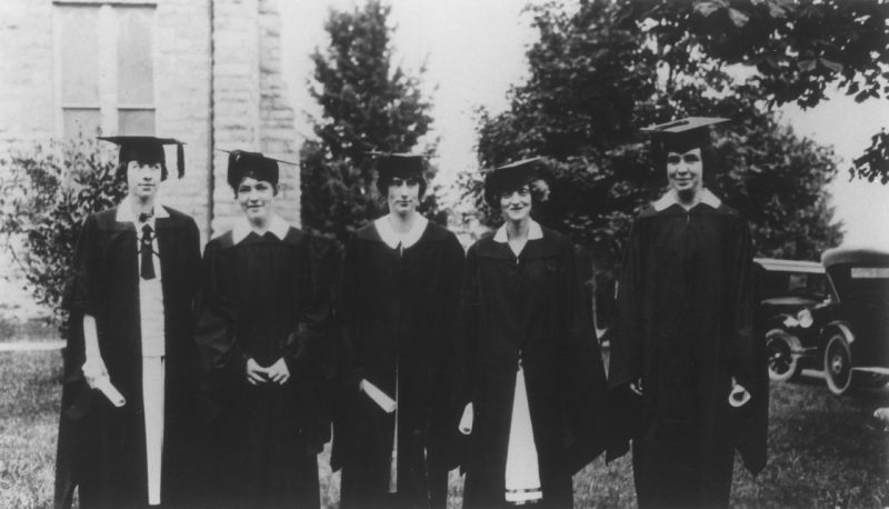 Five female college students wearing caps and gowns.