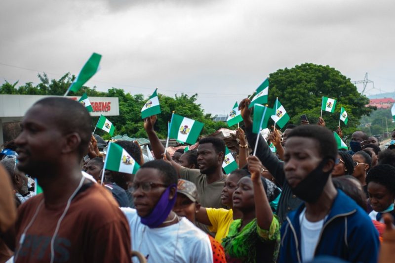 A large group of Nigerians gathered together waving Nigerian flags.