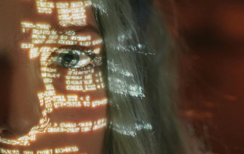 A woman with computer code projected onto her face. Image courtesy Pexels.